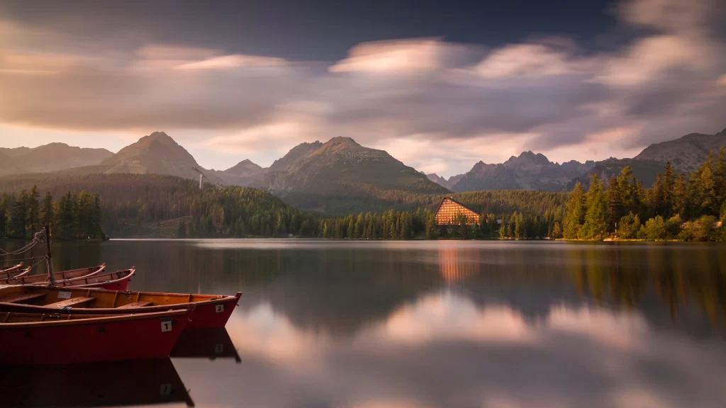 Boats lake mountains trees clouds sunset