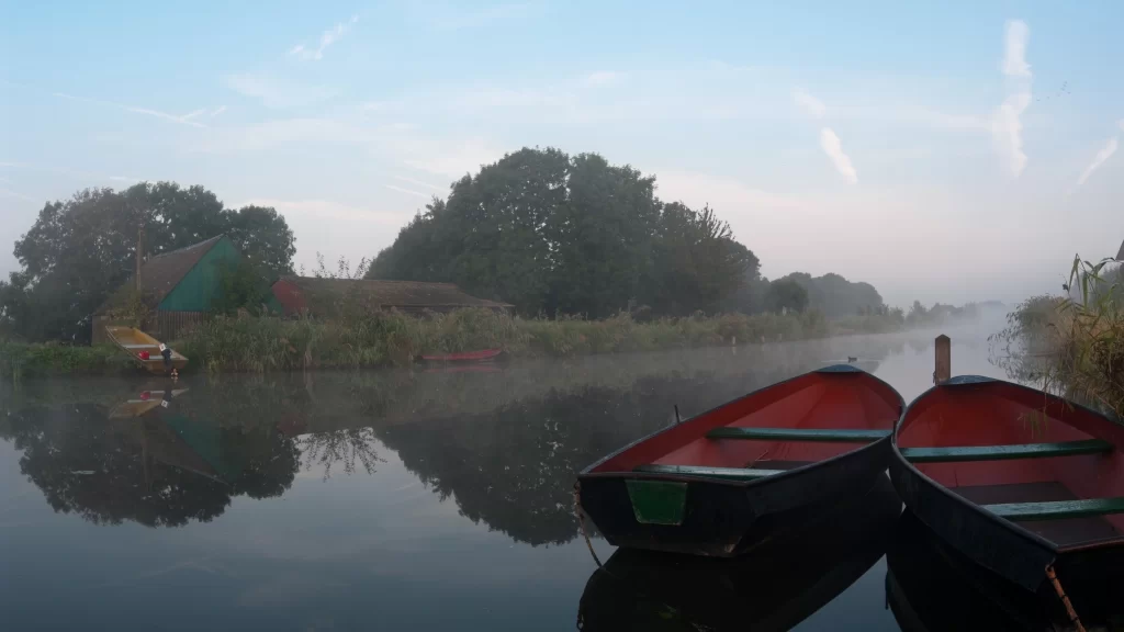 Boats river trees mist buildings reflection calm
