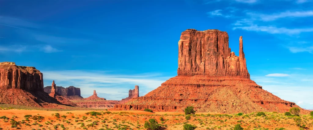 Desert, red rock formations, clear sky, sparse vegetation, natural landscape