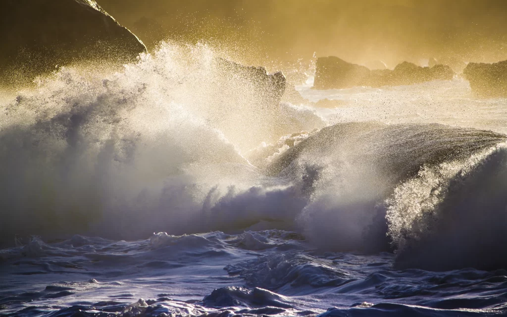 Ocean waves sunlight splashing rocky shore golden glow dynamic water natural bea