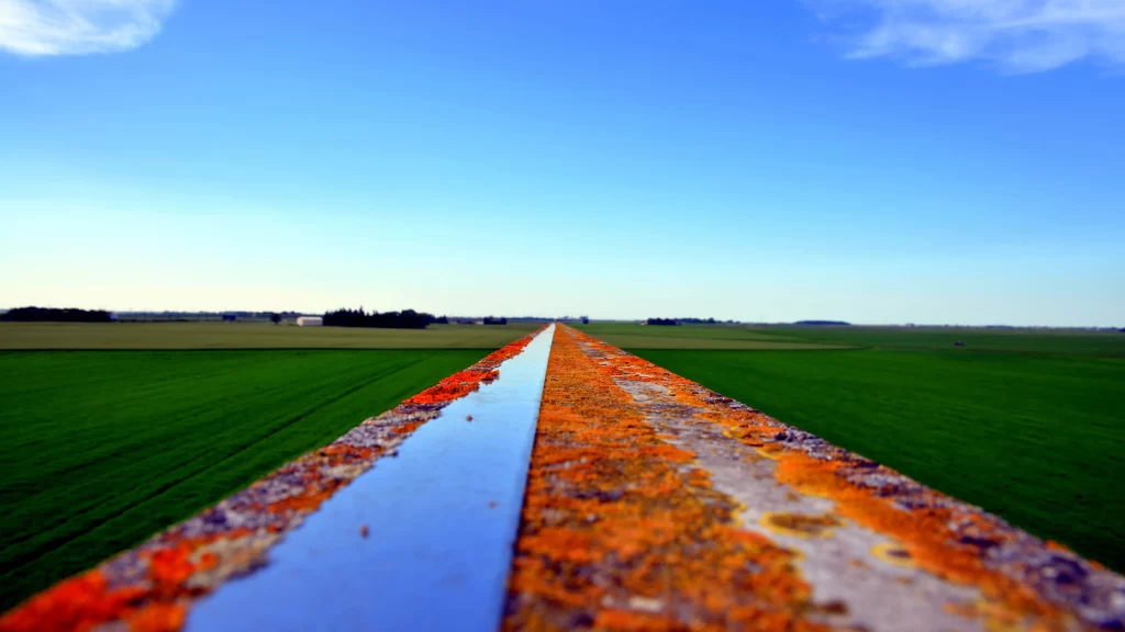 Rust, metal, green field, blue sky, horizon, perspective