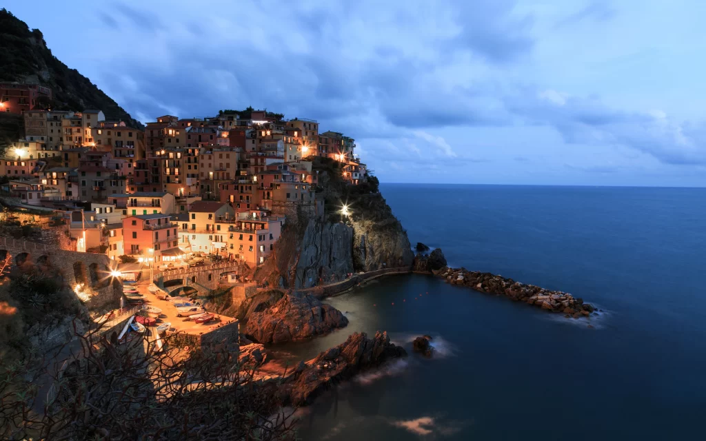 Sea sky buildings lights cliffs clouds