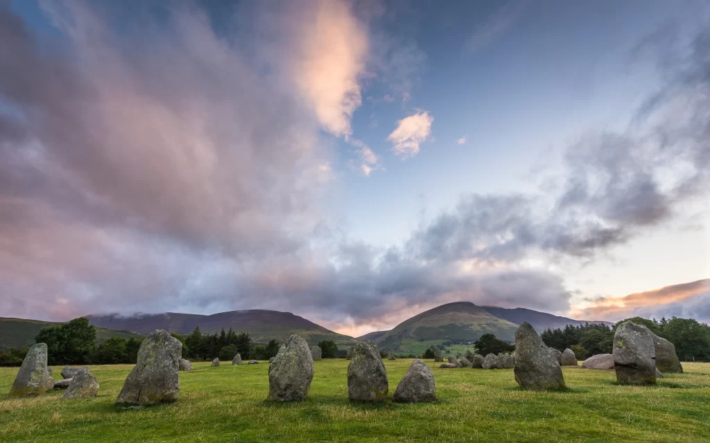 Stone circle green grass mountains clouds sunset landscape