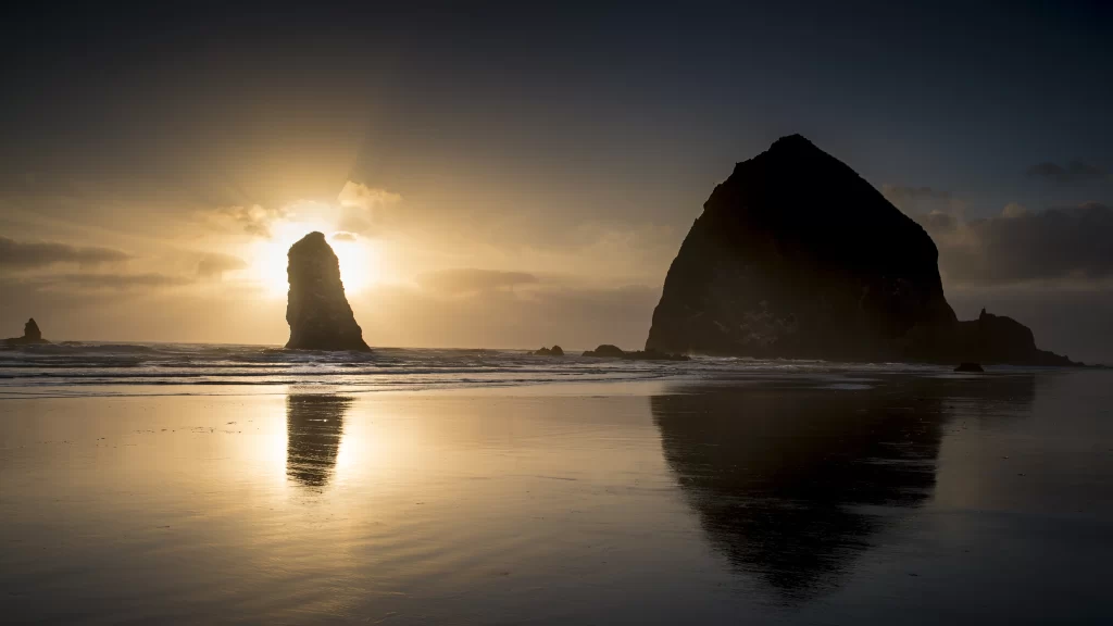 Sunset beach ocean rock formations reflection clouds
