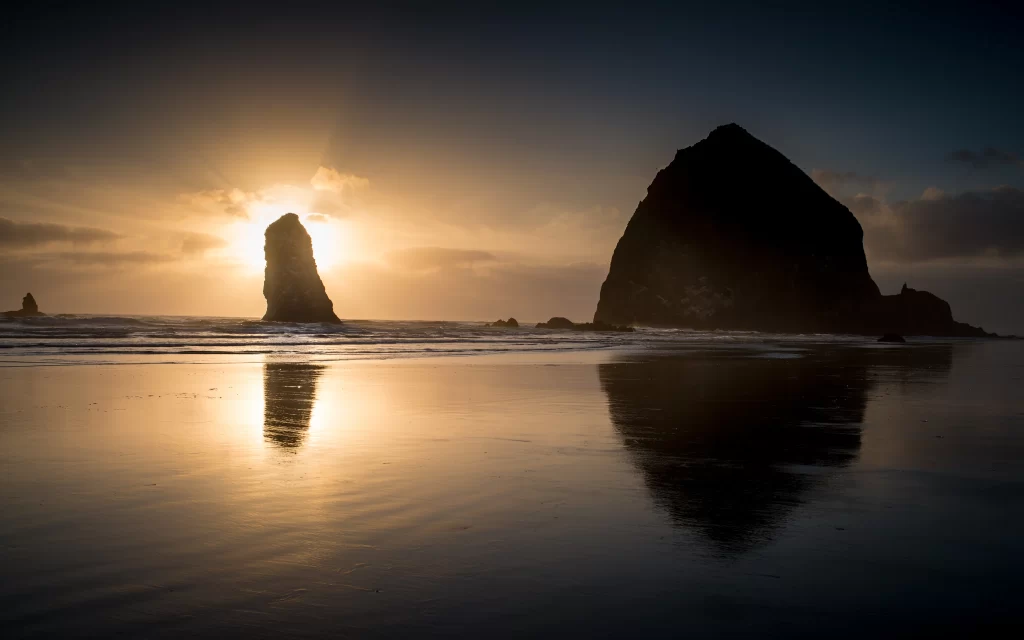 Sunset beach ocean rock formations reflection clouds