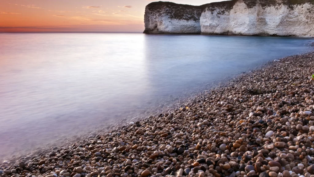 Sunset beach pebbles cliffs ocean sky