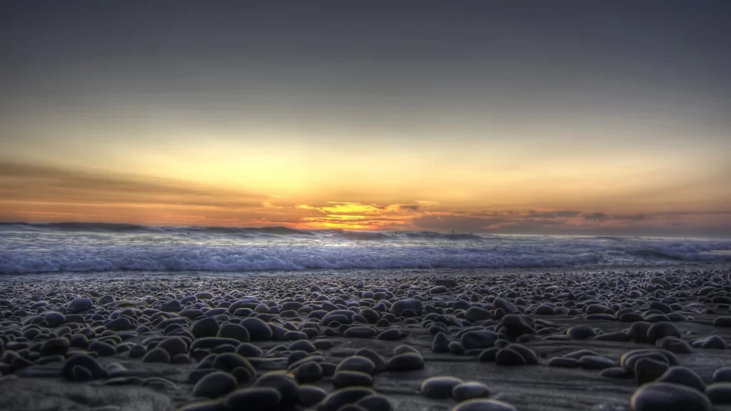 Sunset beach pebbles ocean sky clouds