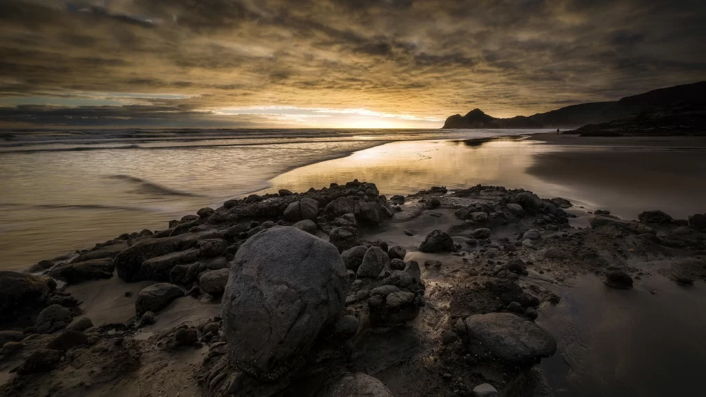 Sunset beach rocks clouds water horizon