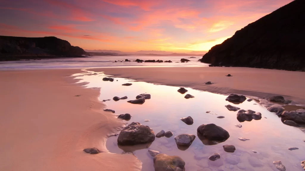 Sunset beach rocks water sky reflection
