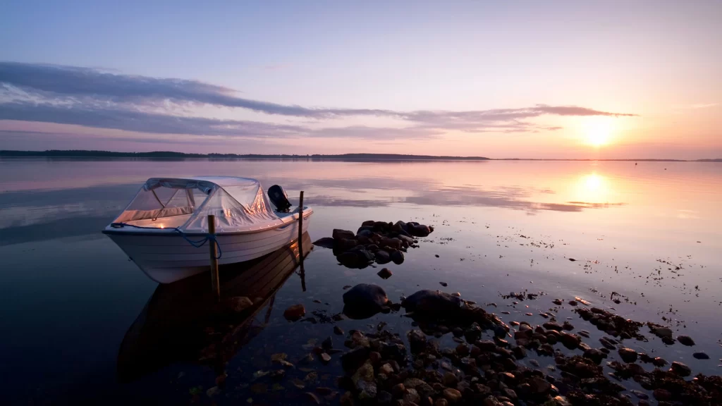 Sunset boat water rocks sky reflection