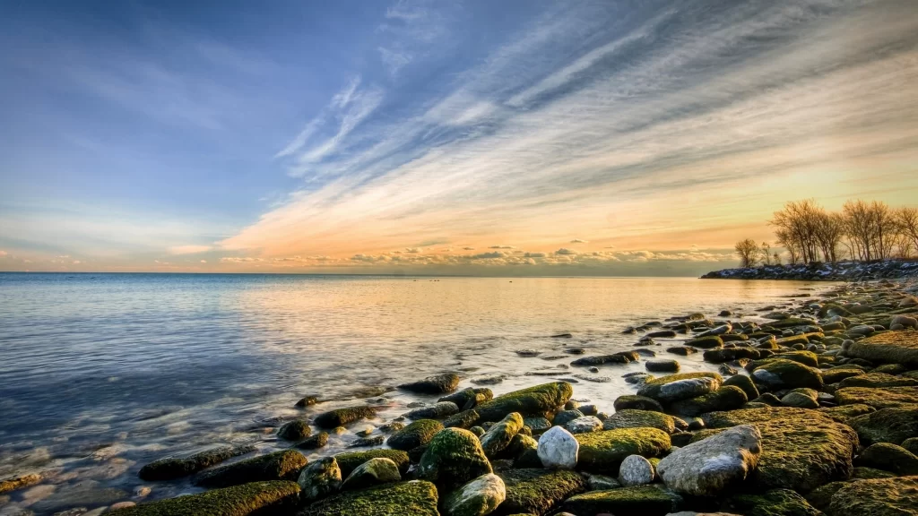 Sunset calm water rocks sky clouds