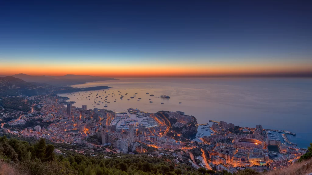 Sunset cityscape ocean boats buildings lights coastline horizon