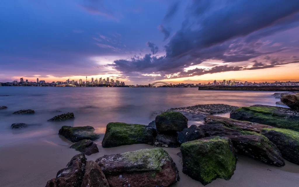 Sunset cityscape skyline water rocks clouds twilight tranquility