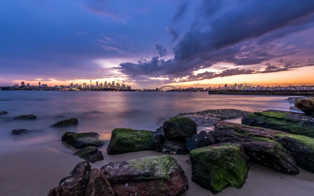 Sunset cityscape skyline water rocks clouds twilight tranquility