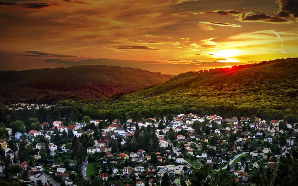 Sunset landscape houses trees hills sky
