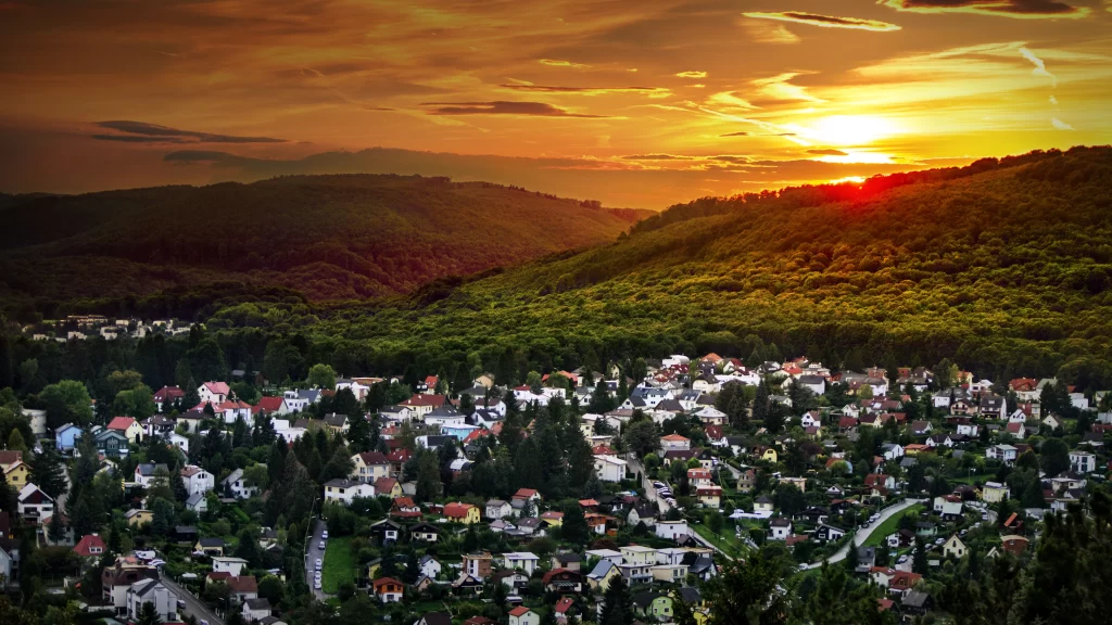Sunset landscape houses trees hills sky