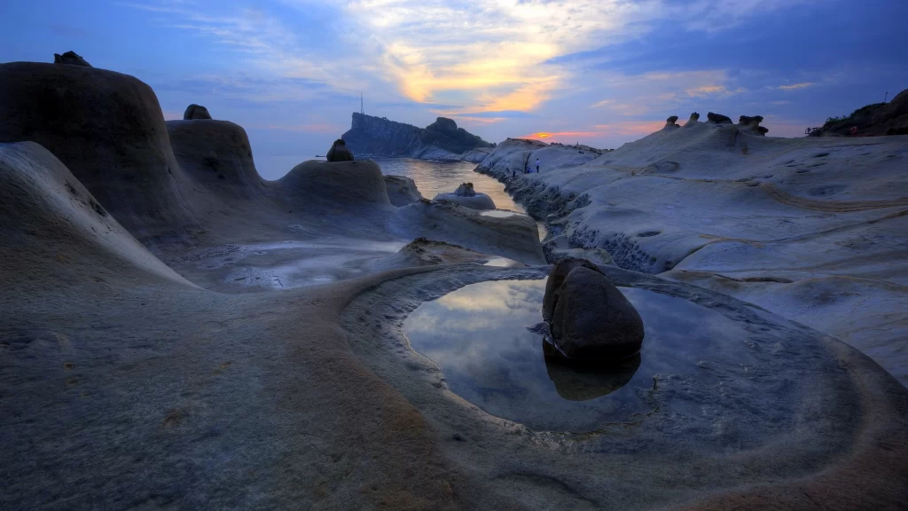 Sunset landscape rock formations water sky clouds