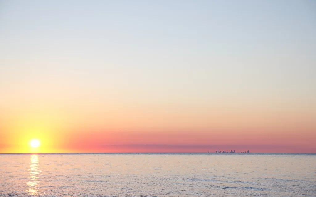 Sunset ocean horizon cityscape calm reflection
