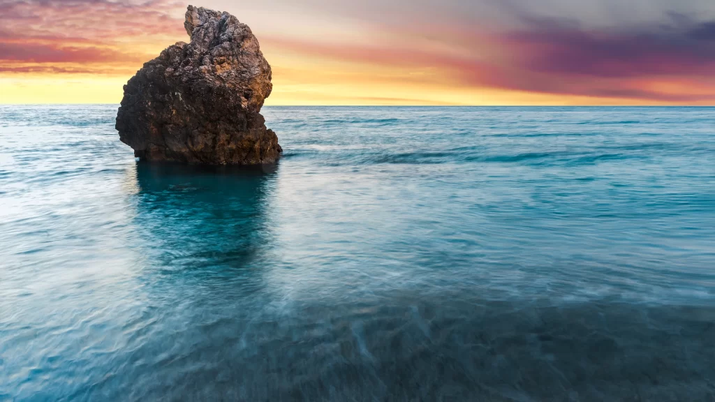 Sunset ocean rock reflection sky clouds