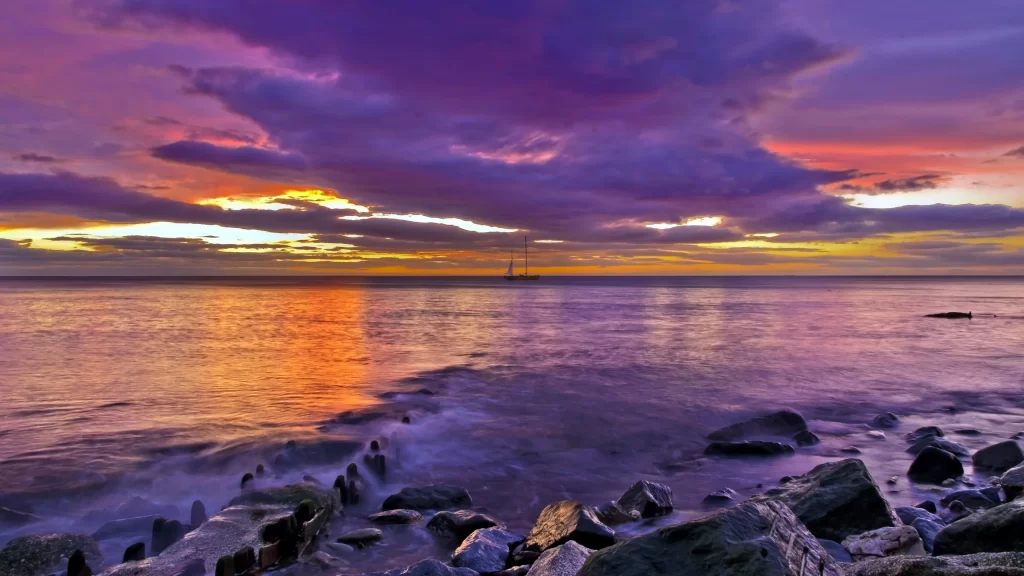 Sunset ocean rocks clouds sailboat reflection