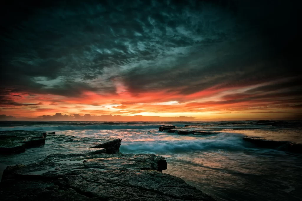 Sunset ocean rocks clouds waves horizon