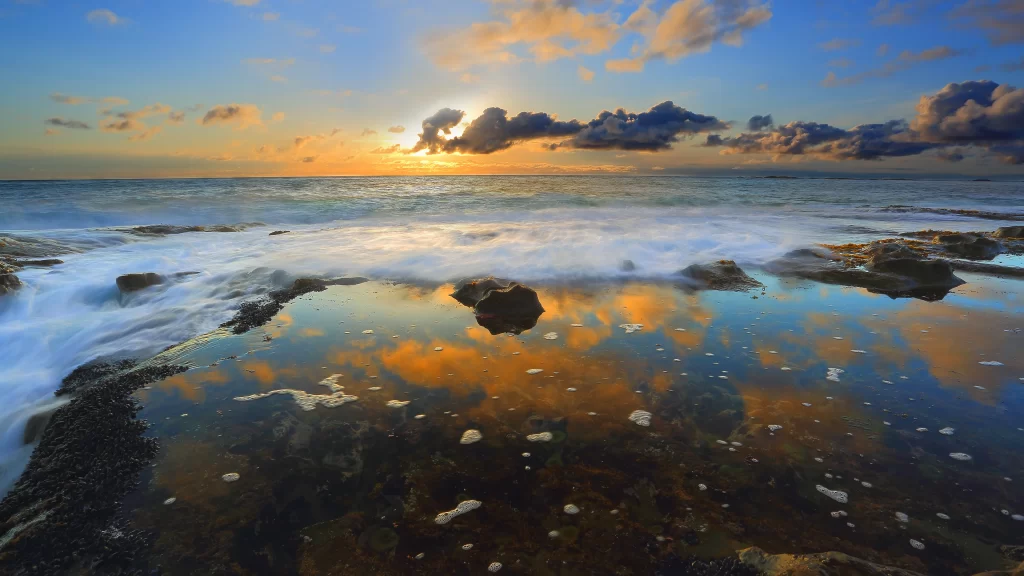 Sunset ocean rocks reflection clouds horizon