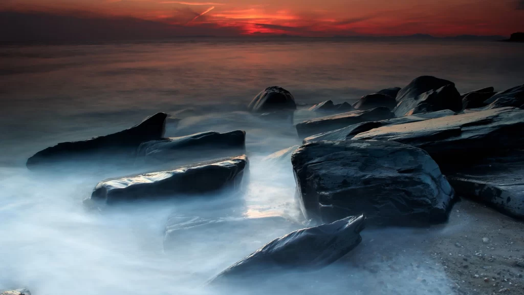 Sunset ocean rocks waves sky clouds