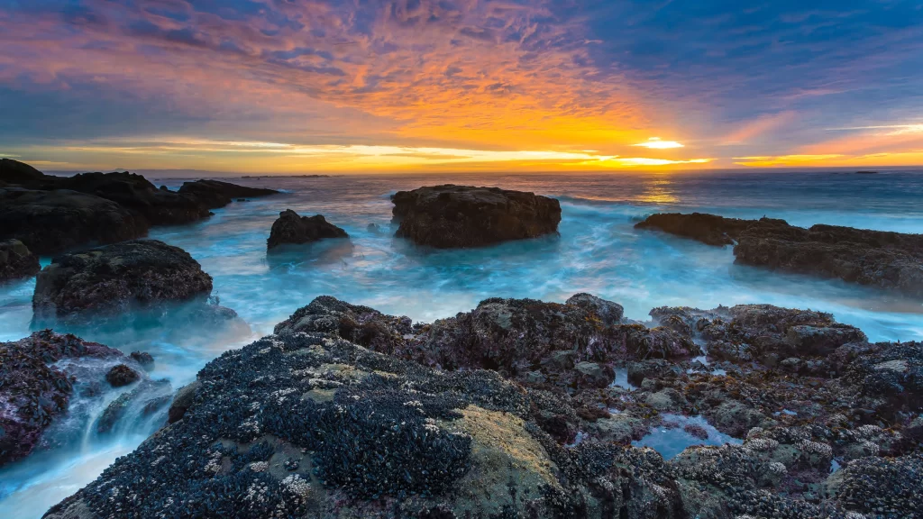Sunset ocean rocks waves sky clouds