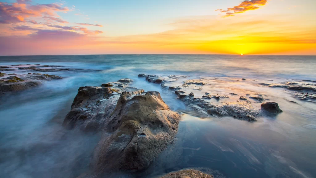 Sunset ocean rocks waves sky clouds