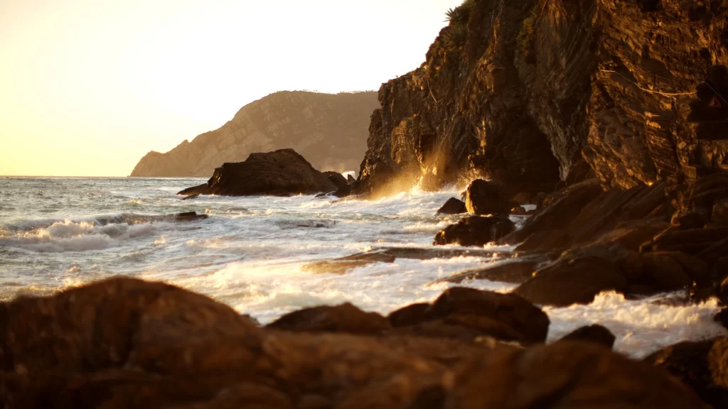 Sunset ocean waves rocks cliffs golden light