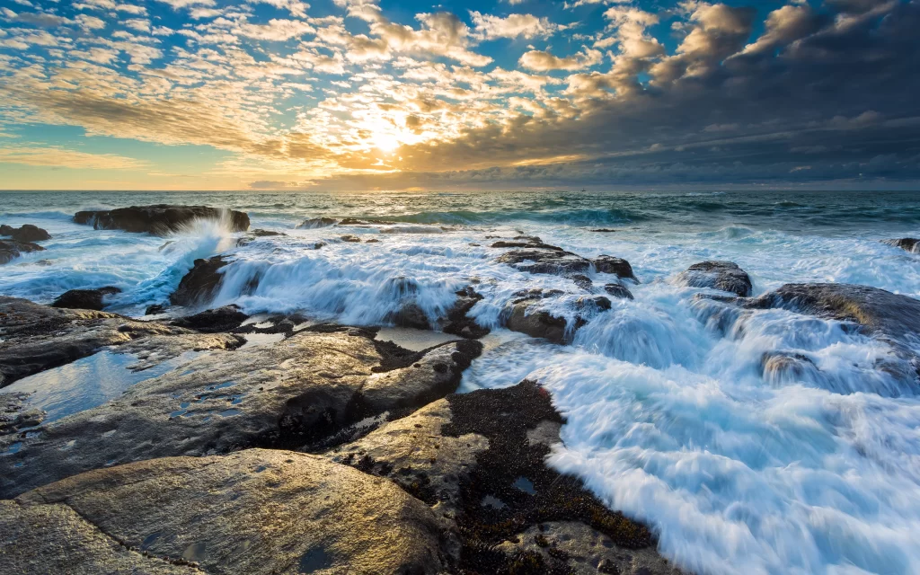 Sunset ocean waves rocks clouds horizon
