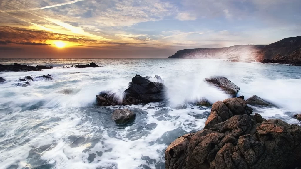 Sunset ocean waves rocks sky clouds
