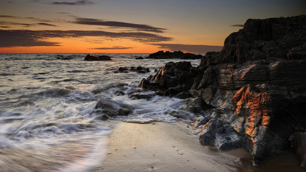 Sunset ocean waves rocks sky clouds