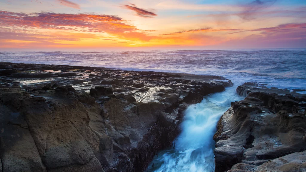 Sunset ocean waves rocks sky clouds