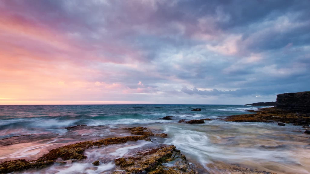 Sunset ocean waves rocks sky clouds