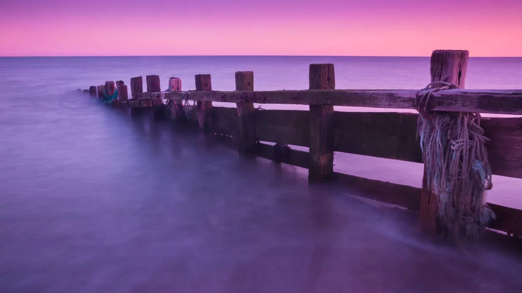 Sunset ocean wooden pier purple sky calm water ropes