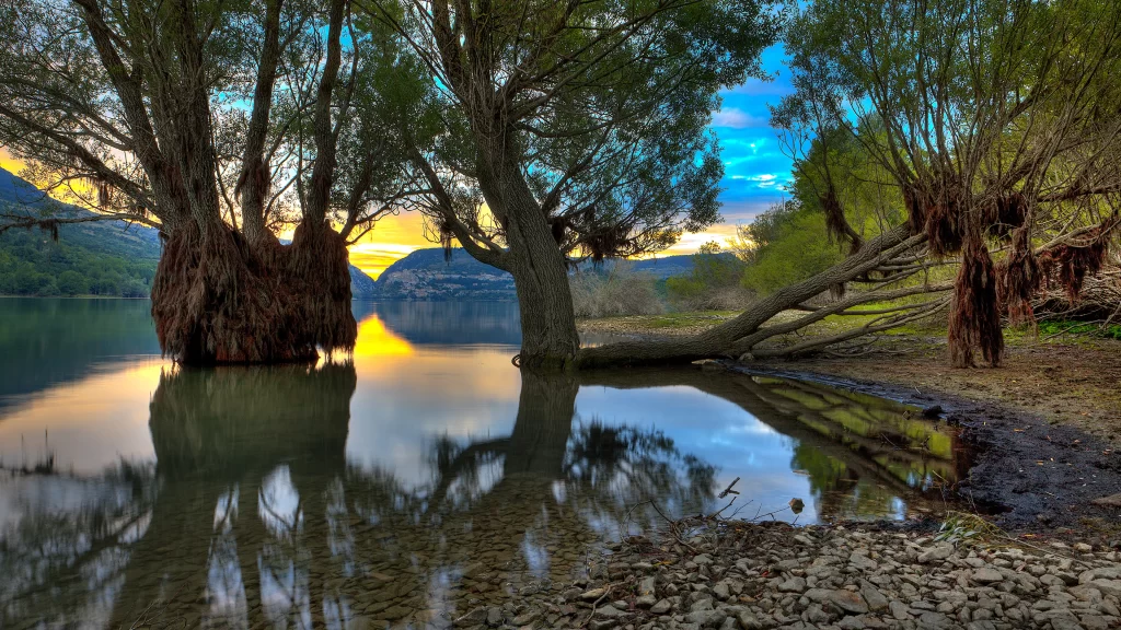 Sunset reflection trees water mountains sky