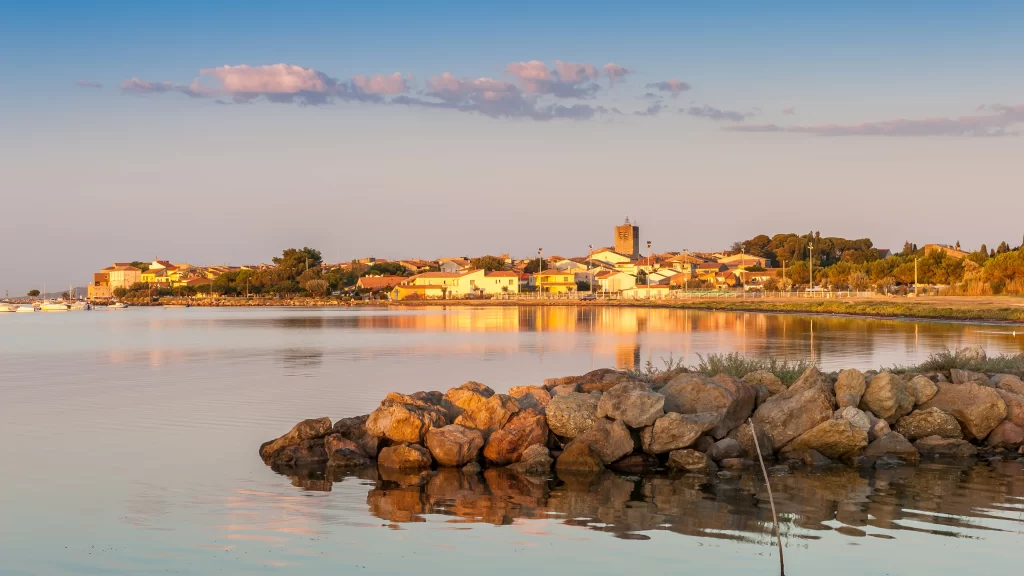 Sunset water reflection rocks town sky clouds