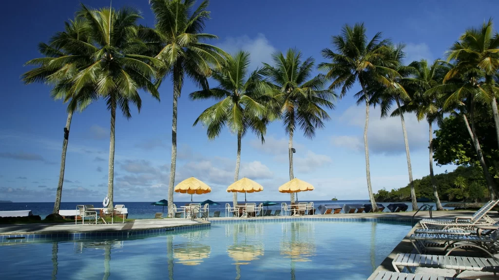 Swimming pool beach palm trees sun umbrellas lounge chairs ocean view