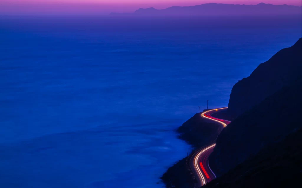 Twilight coastline road lights mountains ocean