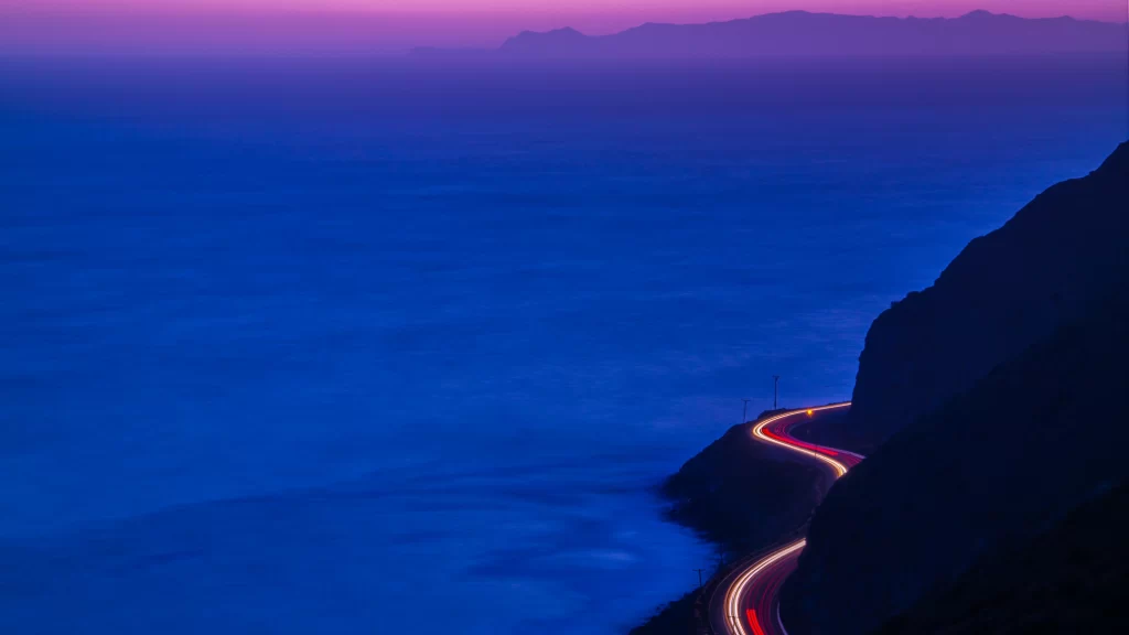 Twilight ocean coastline road lights mountains horizon serenity