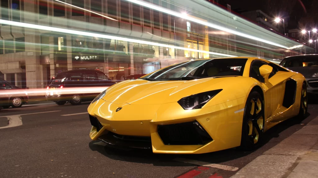 Yellow sports car city street night motion blur luxury urban lights buildings