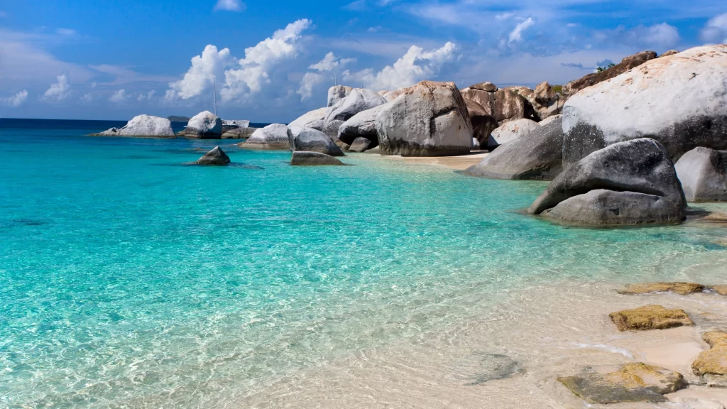 beach ocean rocks clear water blue sky clouds