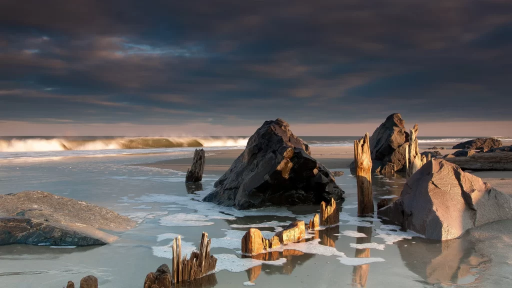 beach rocks waves sky clouds sunset