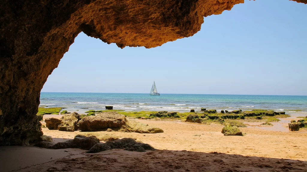 beach sailboat ocean cave rocks sand
