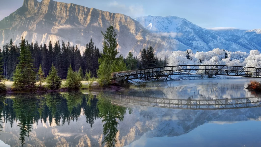 bridge lake mountains trees reflection snow
