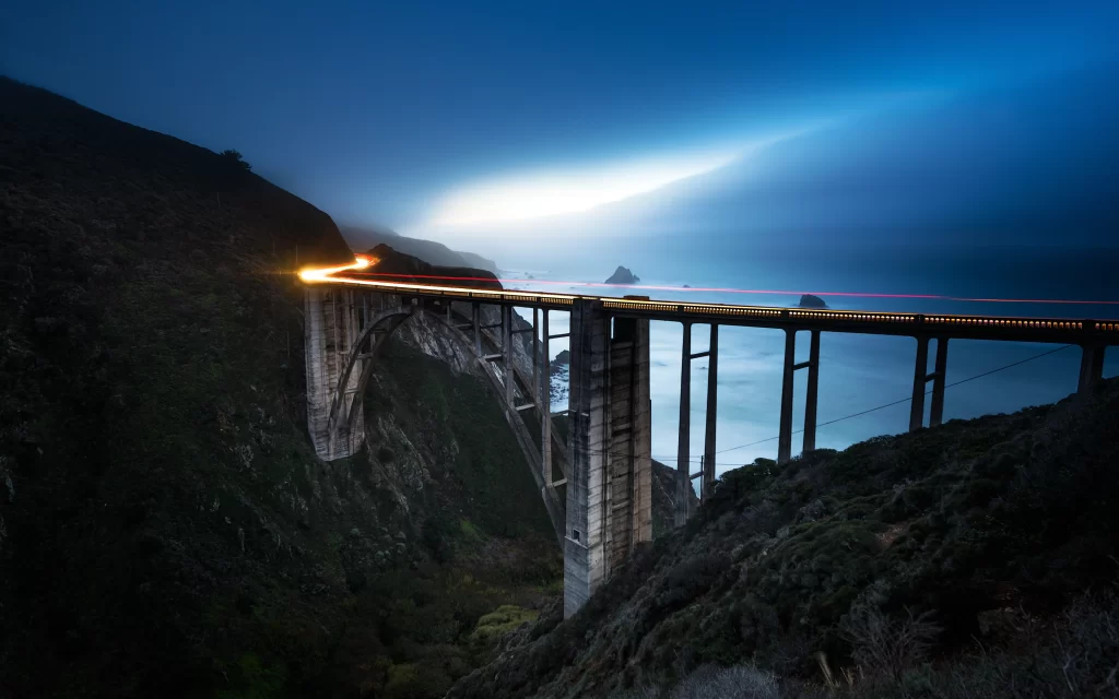 bridge night lights ocean cliffs landscape