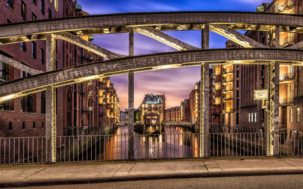 bridge river buildings sunset lights cityscape