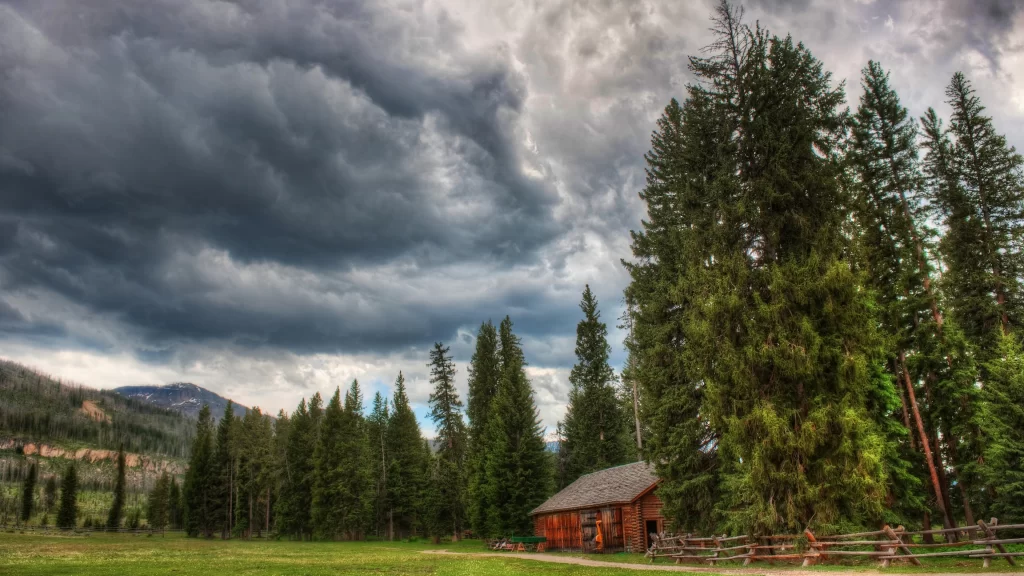 cabin trees clouds grass fence mountains