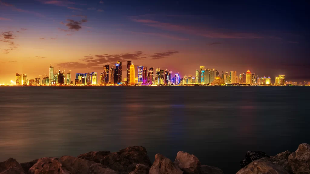 city skyline sunset water buildings lights rocks
